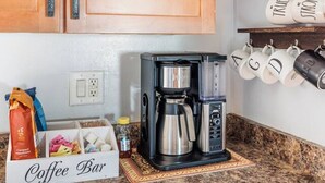 A kitchen with wooden cabinets, a coffee maker, a coffee bar sign, and mugs on a shelf. - Great 4 Groups, Near Everything! (Phoenix)