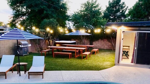 A backyard with a swimming pool, a barbecue grill, a wooden table and chairs, and string lights. - Great 4 Groups, Near Everything! (Phoenix)
