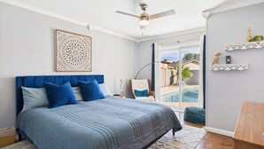 A bedroom with a bed, a ceiling fan, a window with a view of a swimming pool, and a chair by the window. - Great 4 Groups, Near Everything! (Phoenix)