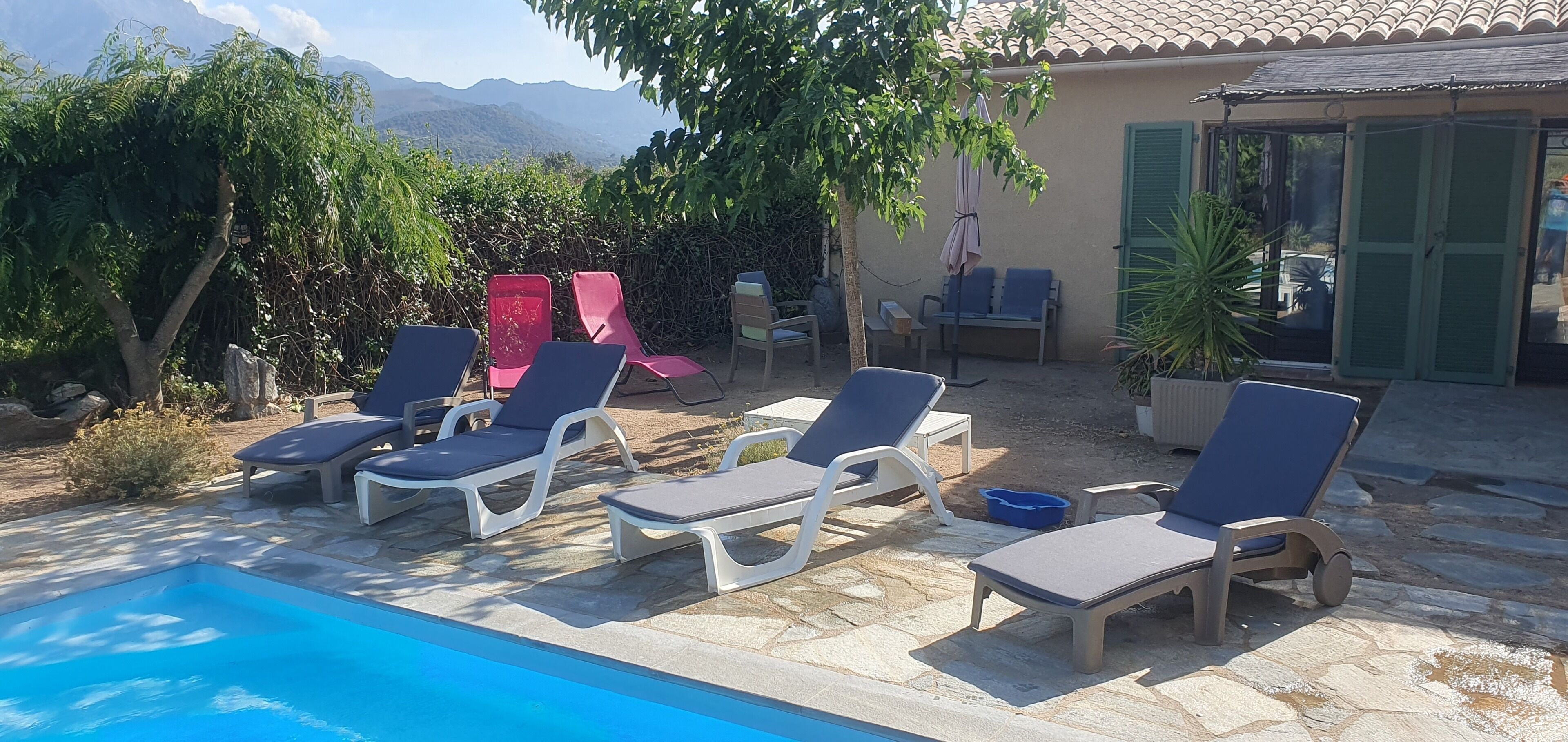 Zona de piscina amb gandules, una piscina petita i vistes a les muntanyes.