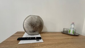 A remote control, a QR code, and a plastic bottle on a wooden table. - Yllen Rooms (Large Double Room) (Avola)