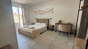 A bedroom with a bed, bedside table, chair, and a painting on the wall. - Yllen Rooms (Large Double Room) (Avola)