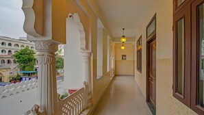 A corridor with ornate columns, a wooden door, and a hanging light fixture. - Utsav Vilas (Jaipur)