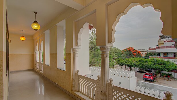 A corridor with ornate white pillars and a balcony with a decorative white railing. - Utsav Vilas (Jaipur)
