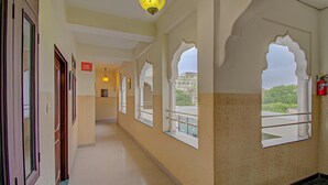 A corridor with arched windows, a sign indicating no smoking, and a fire extinguisher. - Utsav Vilas (Jaipur)