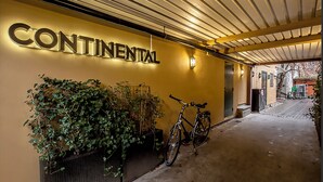 Een hal met een 'Continental' bord, een fiets en een plantenbak met groen.