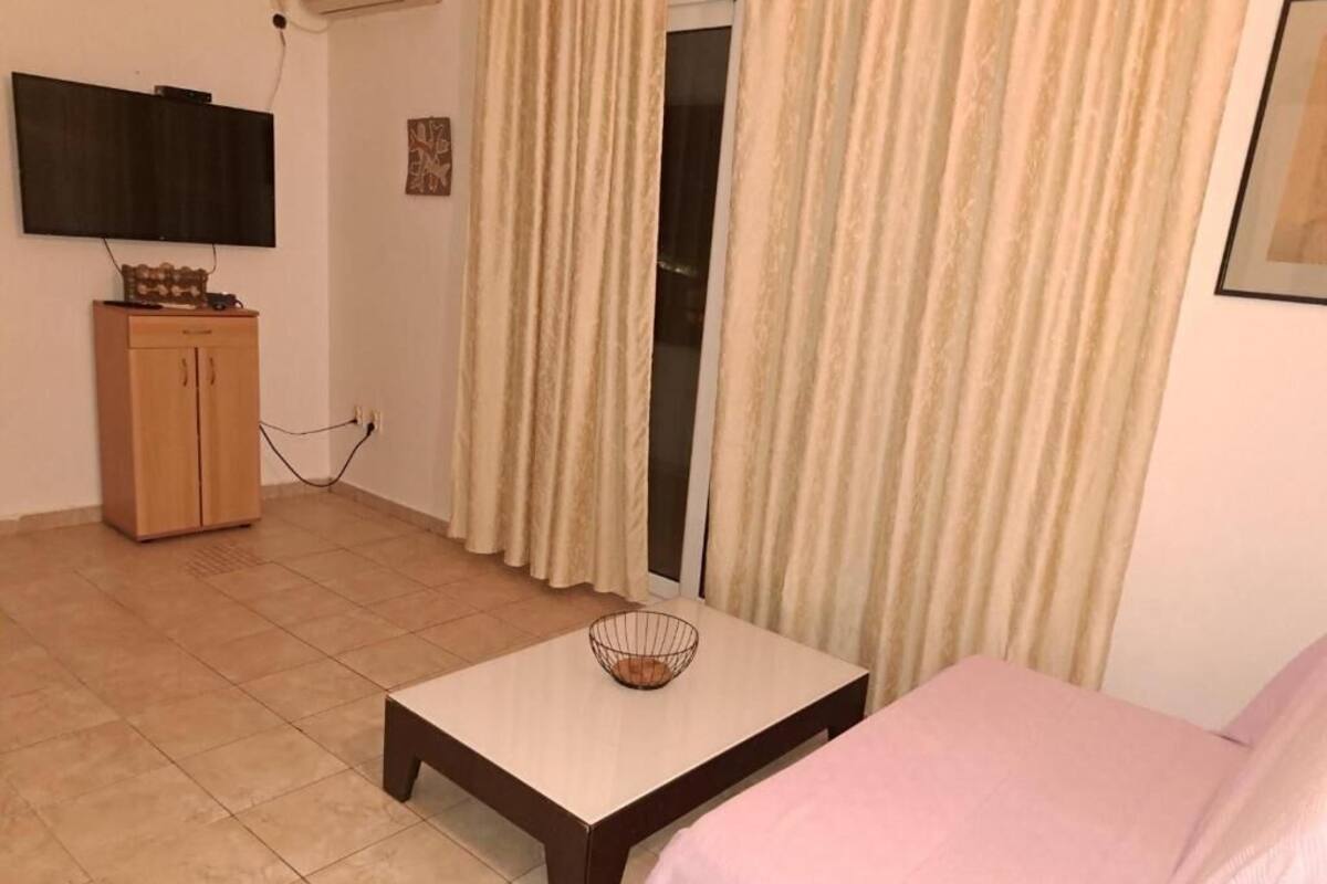 Ein Zimmer mit einem Bett, einem kleinen Tisch mit einer Schale, einem Fernseher an der Wand und einem Holzschrank.