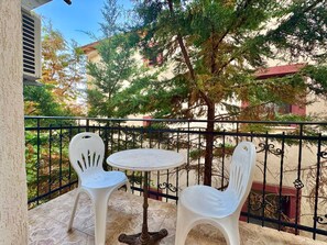 A balcony with two white plastic chairs and a small round table, surrounded by a black wrought iron railing. - The Four Fish Apartments  (Sveti Stefan)