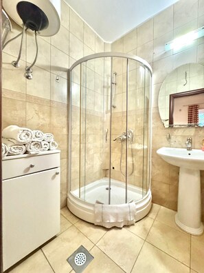 Eenvoudig appartement | Badkamer | Een douche, een haardroger, handdoeken, toiletpapier