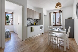 A modern kitchen with white cabinets, a patterned backsplash, and a dining area with a table and chairs. - GuestHost - Carloforte Central Bright Apartment! (Carloforte)