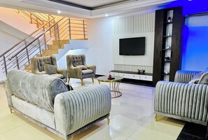 Relax in a spacious living area with a sofa, armchairs, and a large flat-screen TV.