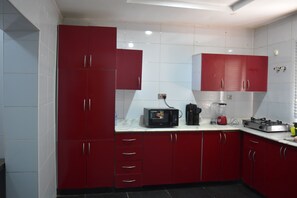 Efficient kitchen with modern design, microwave, coffee maker, and blender, offering ample storage and a practical tile floor.