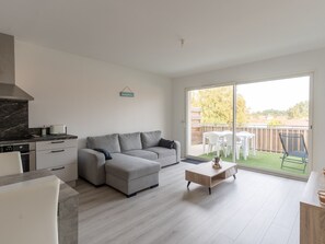 Relax in this stylish living space with a sofa, dining table, and kitchen area, offering a balcony with outdoor seating.
