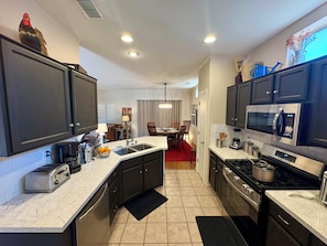 A modern kitchen with dark cabinets, a stainless steel microwave, a gas stove, and a toaster.