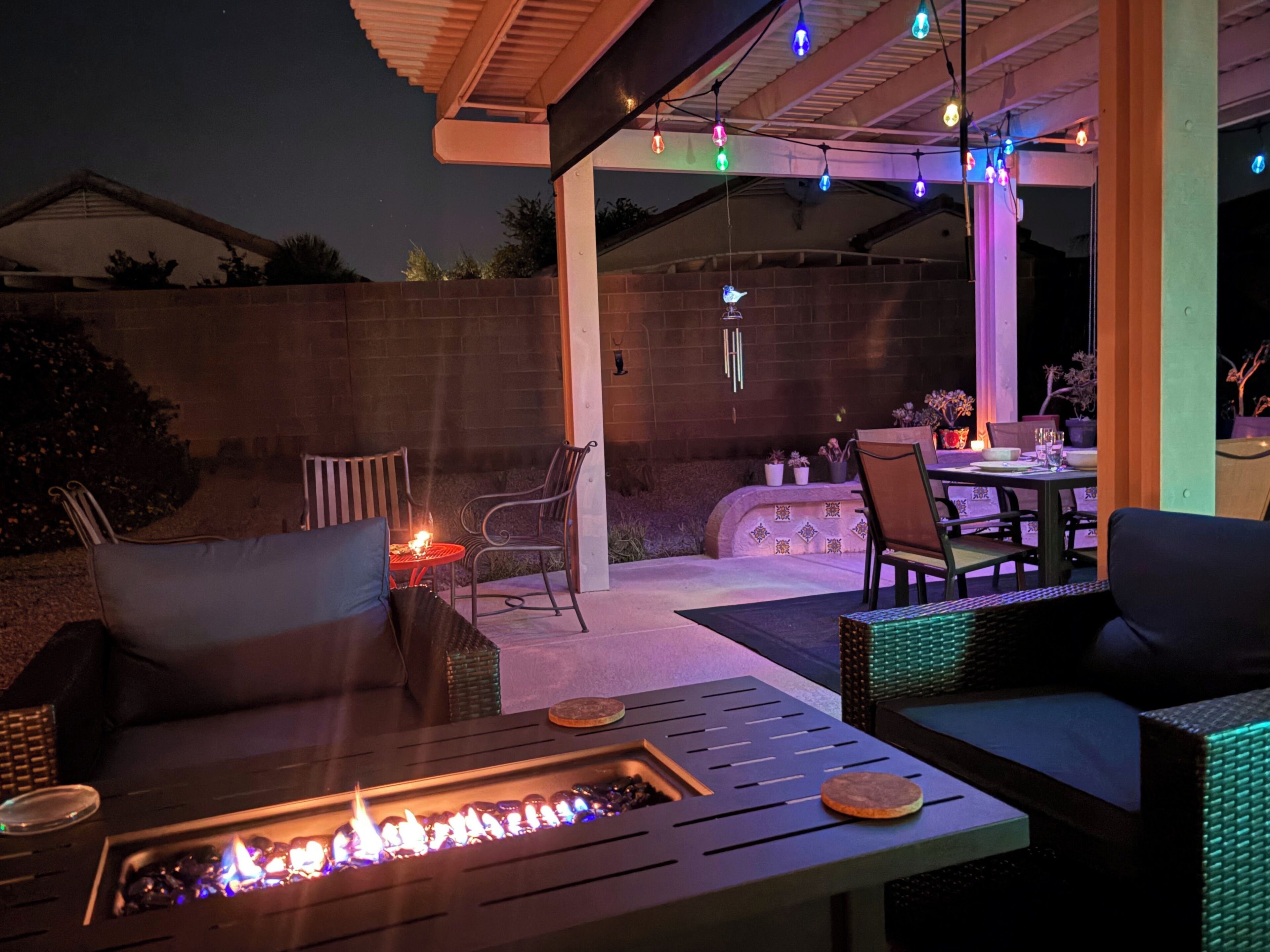 An outdoor patio area with a fire pit, seating, and string lights.