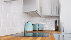 A kitchen with white cabinets, a wooden countertop, and two blue appliances.