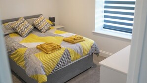 A neatly made bed with patterned bedding and a bedside table with a lamp.