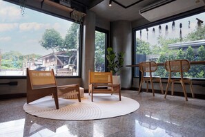 Ein Zimmer mit großen Fenstern, einer runden Sitzecke und einem Blumentopf.