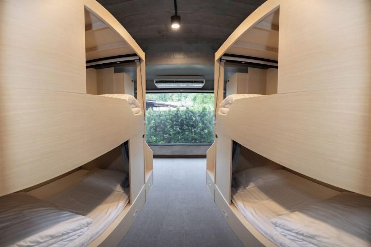 A bunk bed room with a central air vent and a view of greenery outside.