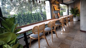 Une longue table en bois, entourée de chaises, avec une plante en pot et un tableau encadré accroché au mur.