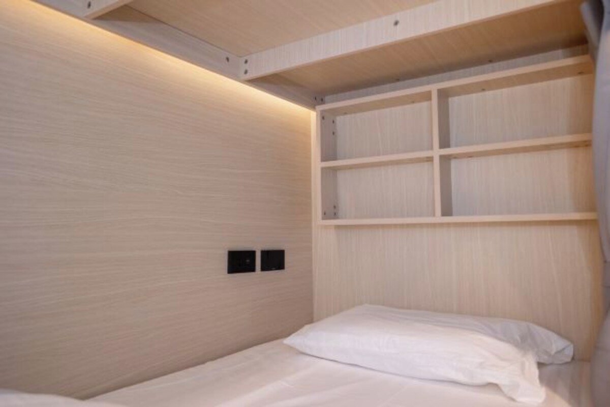 Une chambre à coucher avec un lit, une tête de lit en bois et des étagères intégrées.