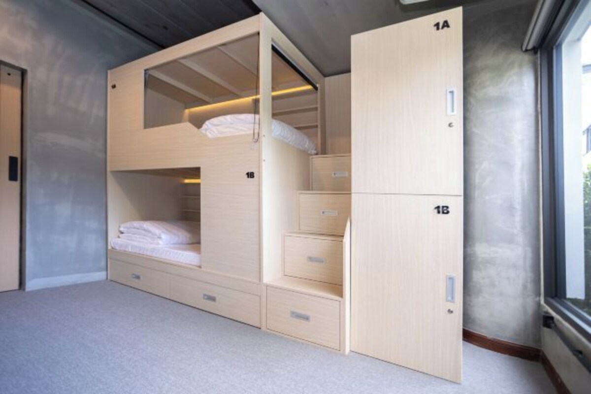 Une chambre avec un lit superposé, un bureau intégré et des tiroirs de rangement.
