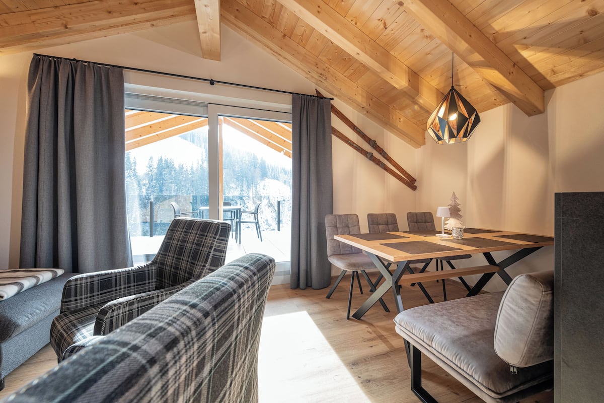 Ein modernes Interieur mit Holzboden, einem Esstisch mit Stühlen und einer Couch.