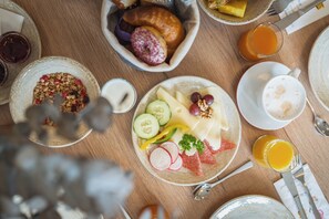 A breakfast setting with various food items and drinks on a wooden table. - AlpenParks Residence Glemmrise Viehhofen (Viehhofen)
