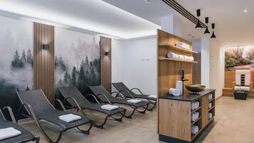 Un espace de détente avec des fauteuils inclinables, un comptoir d’accueil en bois et une fresque murale.