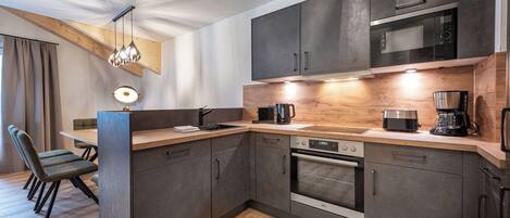 A modern kitchen with dark cabinetry, a wooden countertop, and built-in appliances including a microwave and oven.