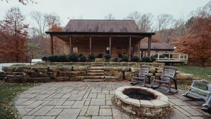 A wooden cabin with a stone fire pit and outdoor seating.