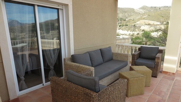 A balcony with wicker furniture, including a sofa and chairs, and a sliding glass door. - beautiful villa with sea and mountain views. (El Campello)