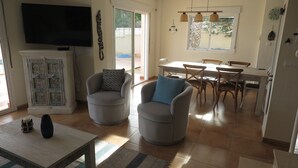 A living room with two armchairs, a TV, a cabinet, and a dining area with a table and chairs. - beautiful villa with sea and mountain views. (El Campello)
