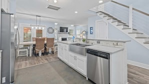 A modern kitchen with white cabinetry, stainless steel appliances, and a built-in dishwasher. - The Costal Haven - 5 Min Beach, 15 Min to DT (Mount Pleasant)