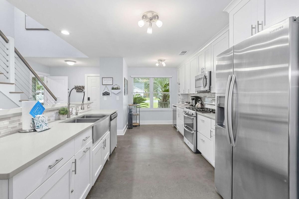 A modern kitchen with stainless steel appliances, white cabinetry, and a central island.