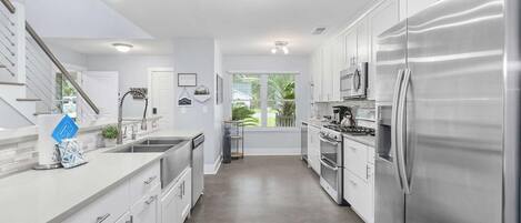 A modern kitchen with stainless steel appliances, white cabinetry, and a central island.