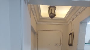 Un pasillo con una puerta blanca, un tapete estampado y una lámpara en el techo.