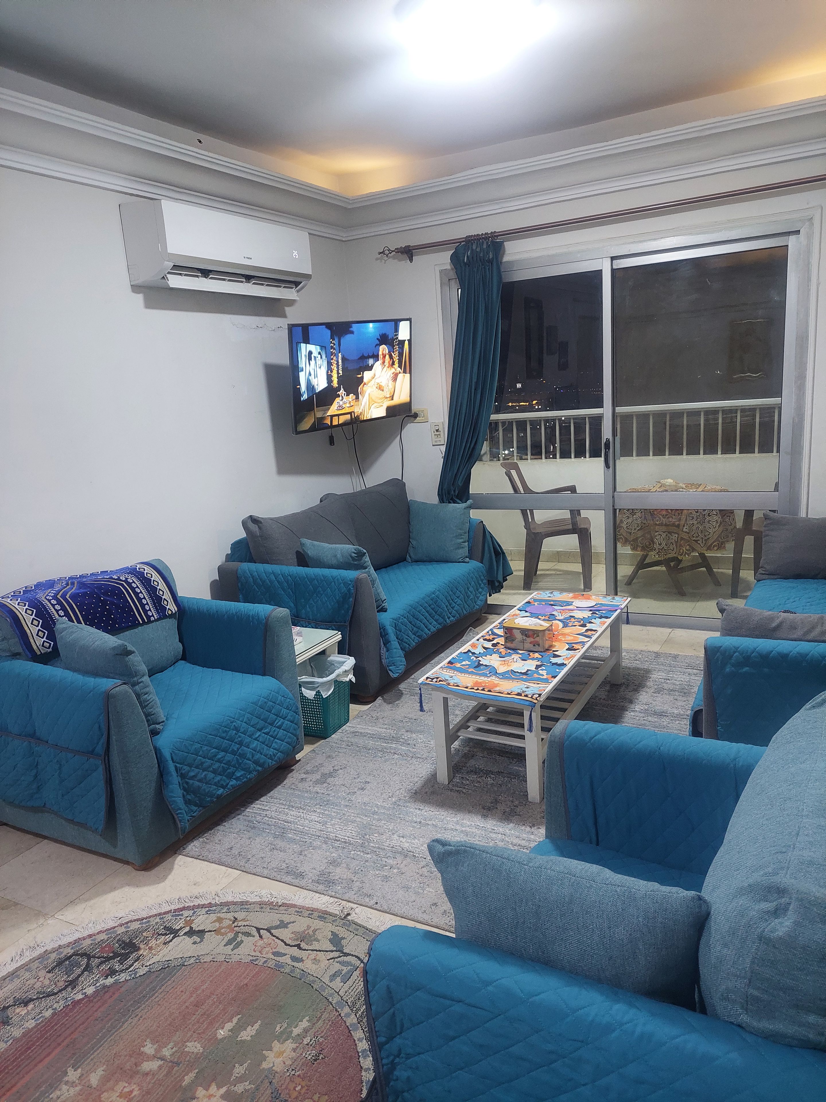 A living room with a sofa set, a coffee table, and a television mounted on the wall.