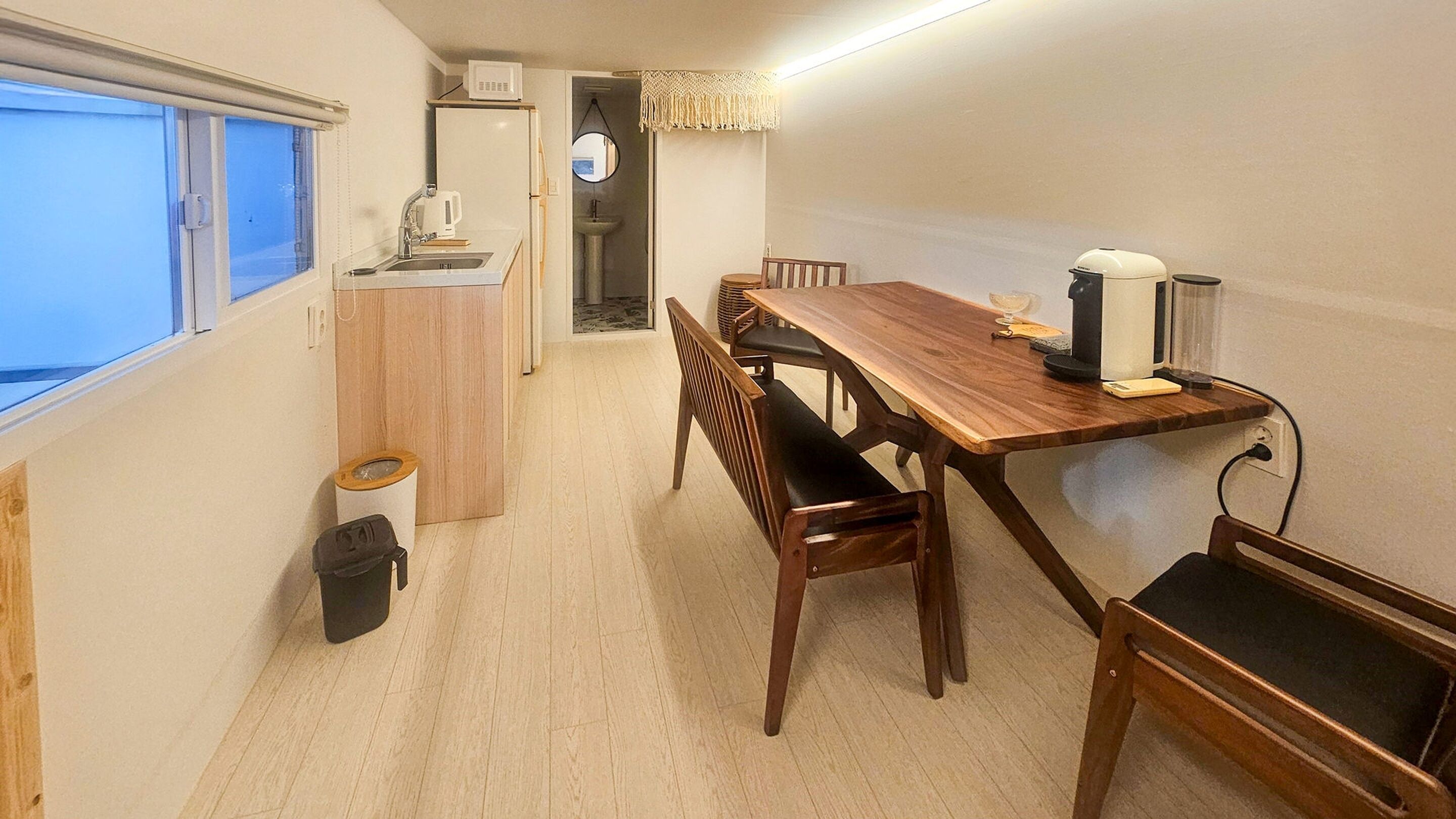 A compact kitchen with a sink, microwave, and a small dining area with a wooden table and chairs.