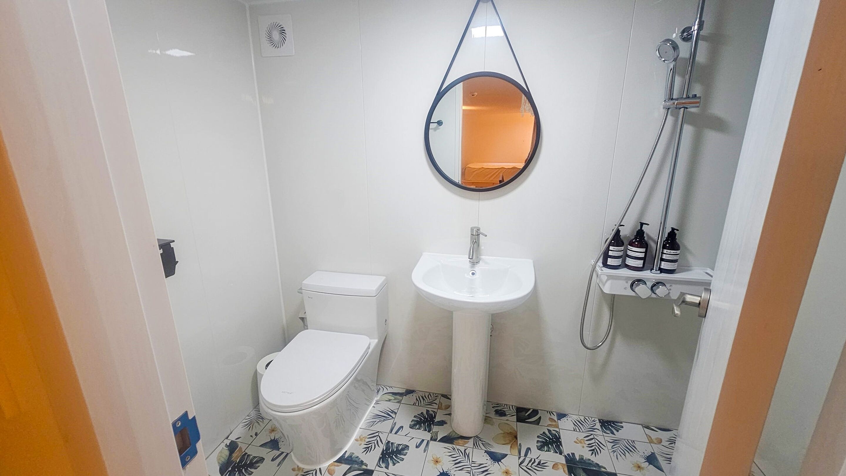 Un baño pequeño con inodoro, lavamanos y ducha.