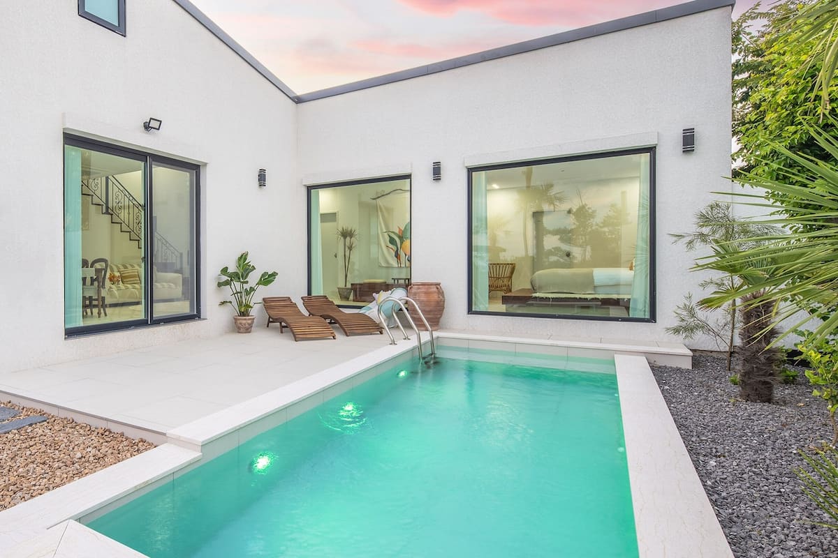 Ein modernes Haus mit Schwimmbad, großen Fenstern und einer Treppe, die zu einem Balkon führt.