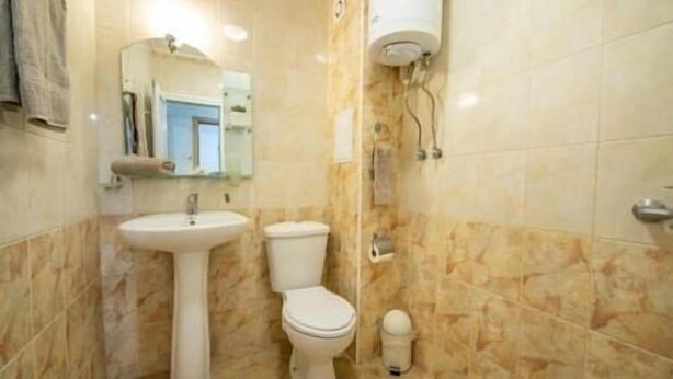 Une salle de bain équipée d’un lavabo, de toilettes et d’un porte-rouleau de papier toilette.
