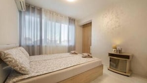 Une chambre à coucher avec un lit, une table de chevet et une fenêtre avec des rideaux.