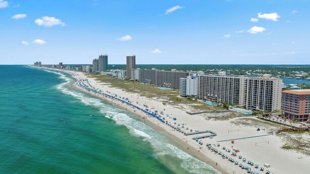 A coastal hotel with multiple high-rise buildings, a long beachfront, and a clear view of the ocean.