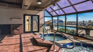 A hot tub area with a view of a pool and outdoor scenery.