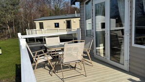 Una terraza con mobiliario exterior y un ventanal corredera que da a un espacio cubierto.
