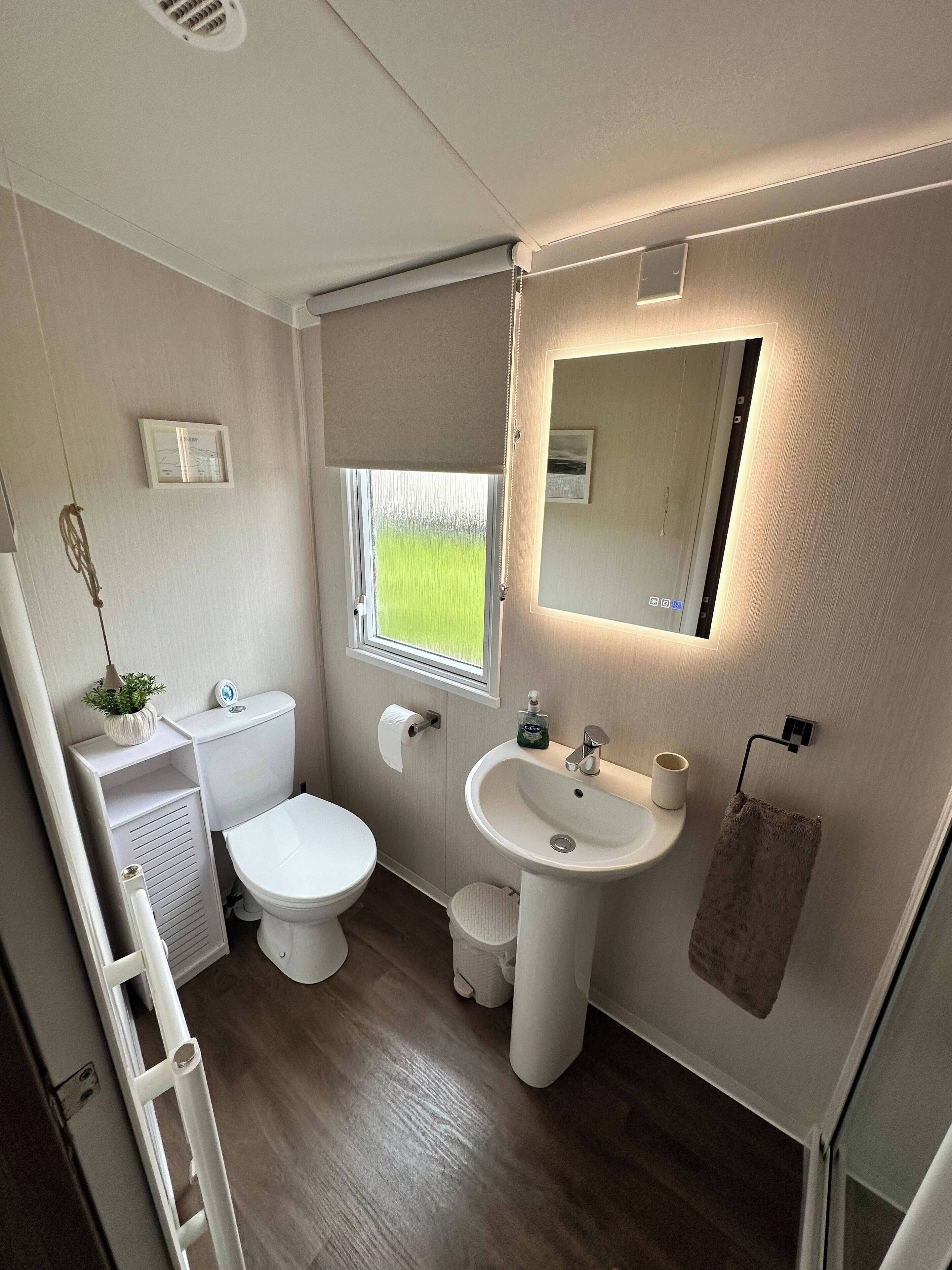 Une petite salle de bain comprenant des toilettes, un lavabo et une fenêtre.