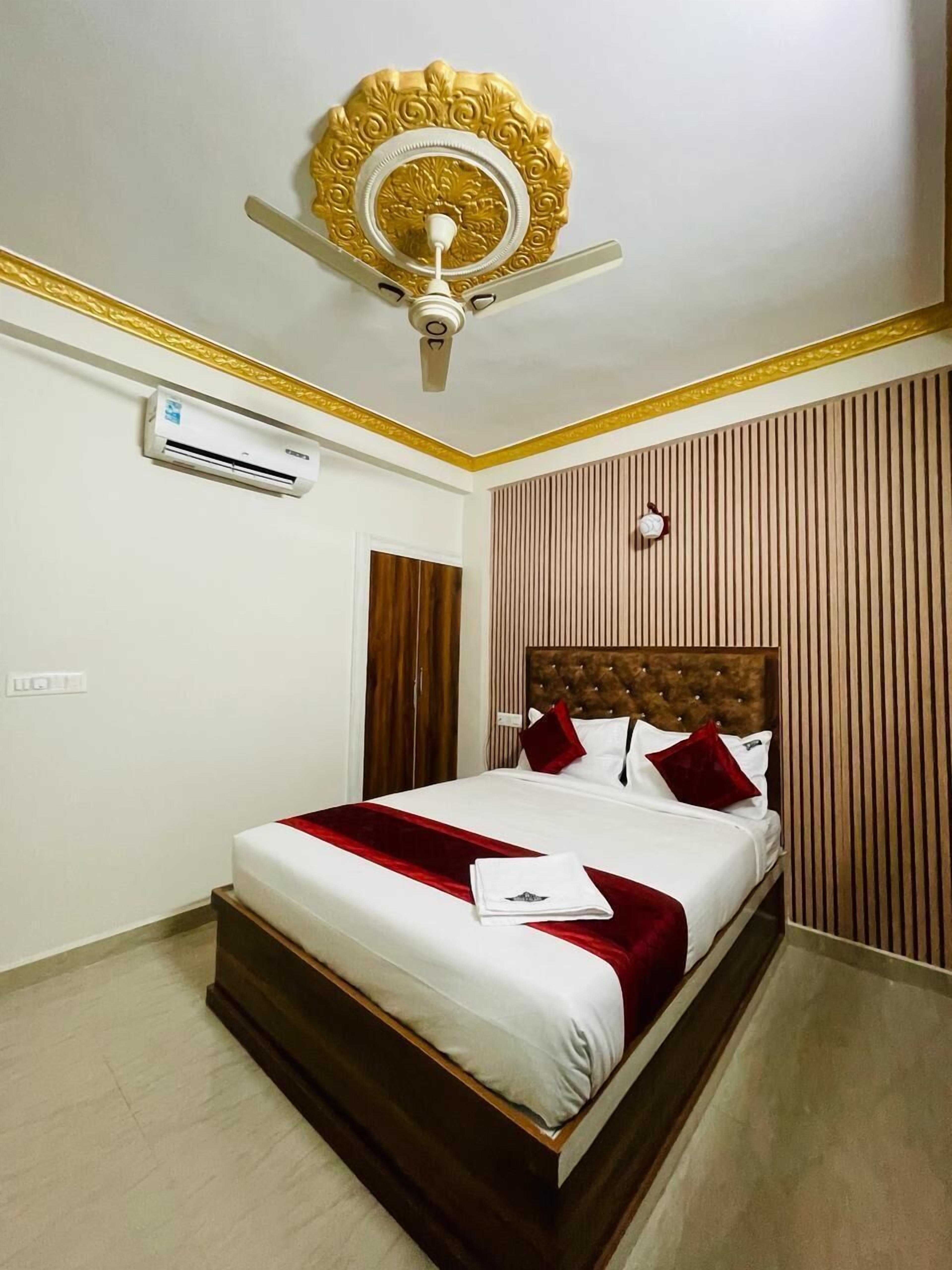 Une chambre d’hôtel équipée d’un lit, d’un ventilateur de plafond, d’un appareil de climatisation et d’un mur recouvert de panneaux de bois.