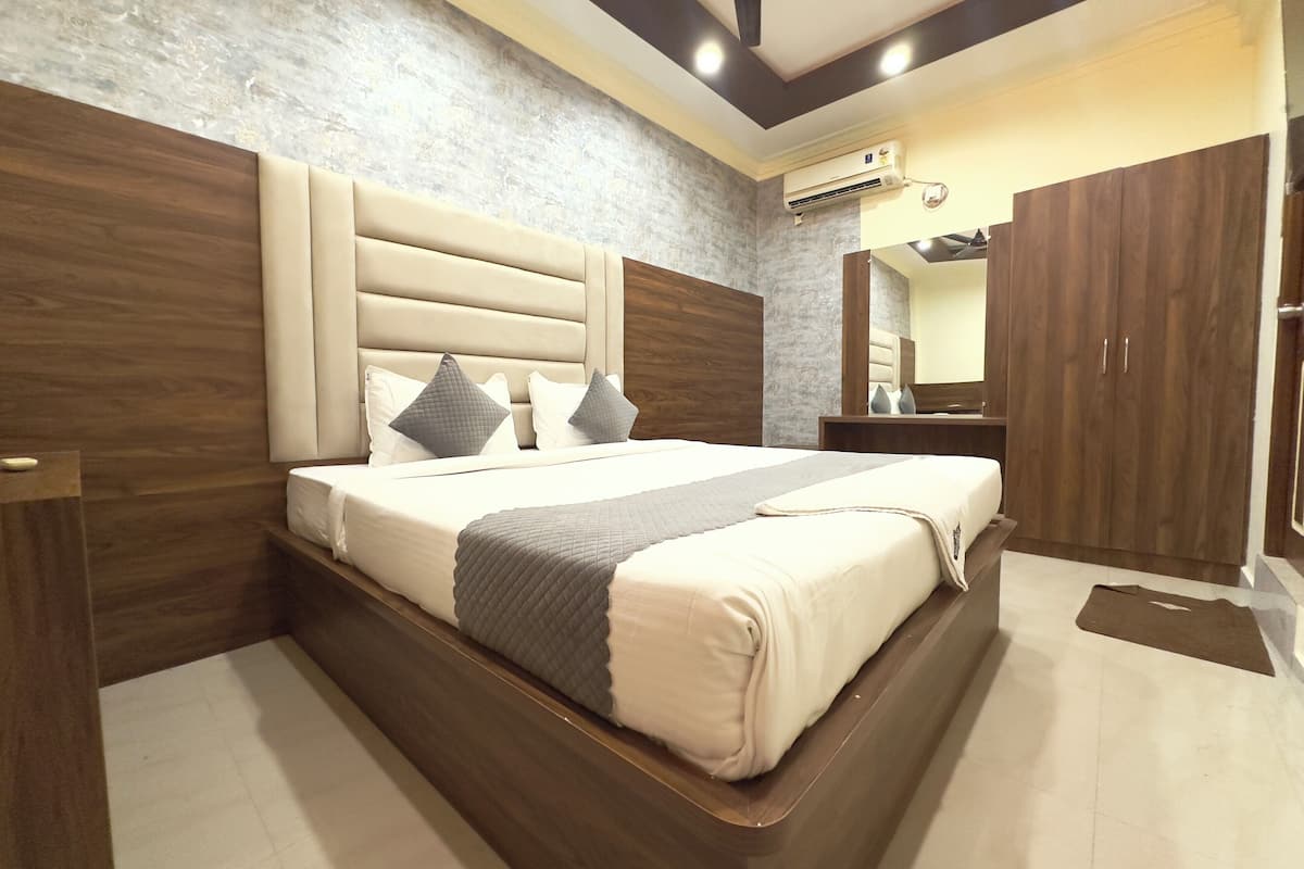 Quarto moderno com cama grande, cabeceira de madeira e guarda-roupa.