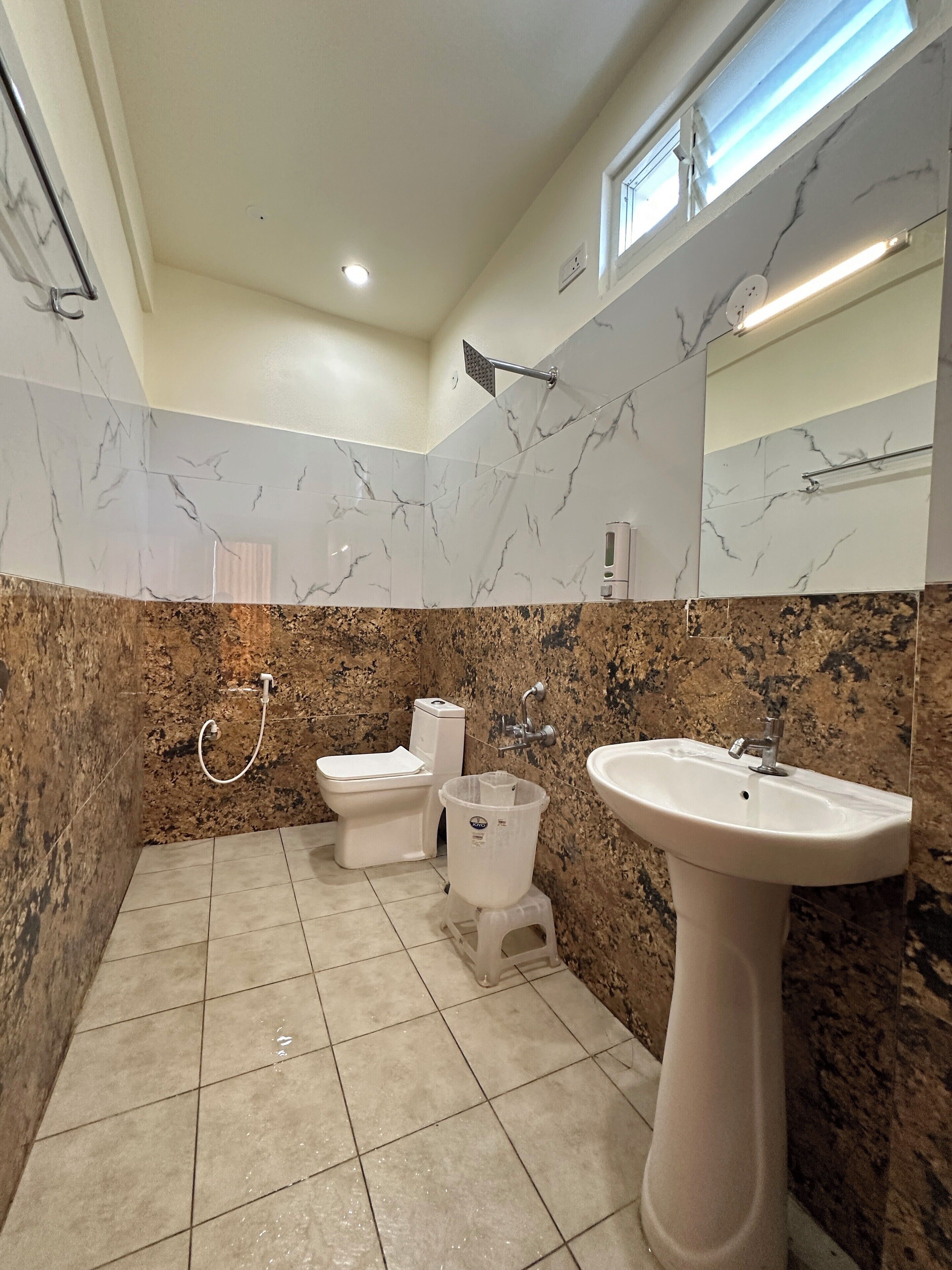 Un baño con tocador de mármol, lavamanos, inodoro y ducha.